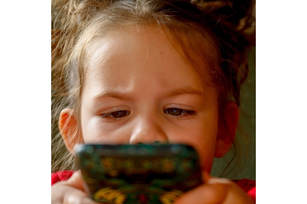 Image Little girl looking suspicious while holding a phone